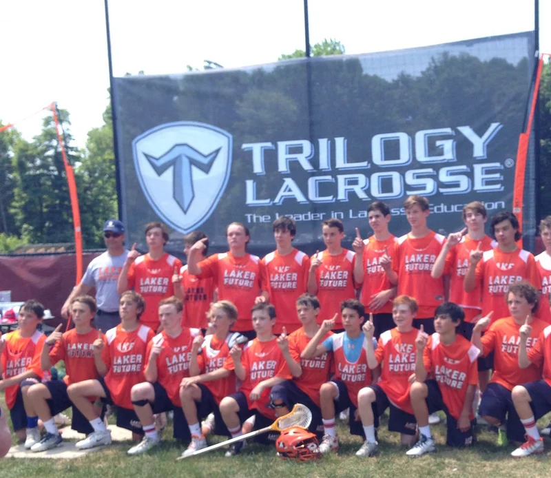 Printed mesh banner displayed behind a lacrosse team at an outdoor sports event